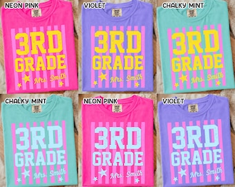 May include: A collection of six t-shirts in various colors, including neon pink, violet, and chalky mint. Each shirt features the text "3RD GRADE" in a bold font, with "Mrs. Smith" below. The design includes vertical stripes and star accents.