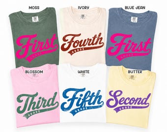 May include: Six short-sleeve t-shirts in moss, ivory, blue jean, blossom, white, and butter colors. Each shirt features a distressed-style graphic with the text First Grade, Fourth Grade, First Grade, Third Grade, Fifth Grade, or Second Grade.