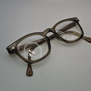 May include: A white ceramic mug with a black handle and the text "But First, Coffee" in a handwritten style. The mug is on a white surface. The mug is approximately 4 inches tall.