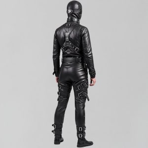 May include: A black leather outfit, including a jacket, pants, and a hood, is shown from the back. The jacket has a harness-like detail across the shoulders. The pants feature multiple straps with buckles. The outfit is worn with black boots.