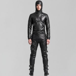 May include: A black leather outfit featuring a hooded jacket with a cross-body strap design, matching pants, and boots. The jacket has a high collar and the pants have multiple straps and buckles. The outfit is all black and appears to be made of leather.