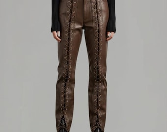 May include: Brown leather pants with a lace-up design along the front seams. The pants have a high waist and are paired with black shoes. The overall style is edgy and fashionable.