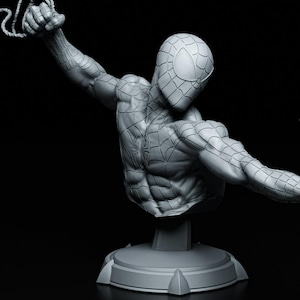 May include: A gray bust of Spider-Man in a dynamic pose, with one arm extended and holding a web. The sculpture features detailed musculature and the character's iconic mask. The bust is mounted on a circular base against a black background.