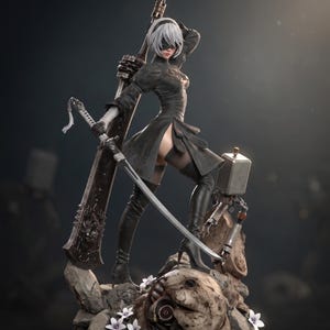 Pode incluir: Uma estatueta detalhada de um personagem com cabelo branco curto, vestindo um vestido preto, luvas e botas altas, segurando uma espada grande. A figura está sobre uma base rochosa com pequenas flores brancas e um companheiro mecânico.