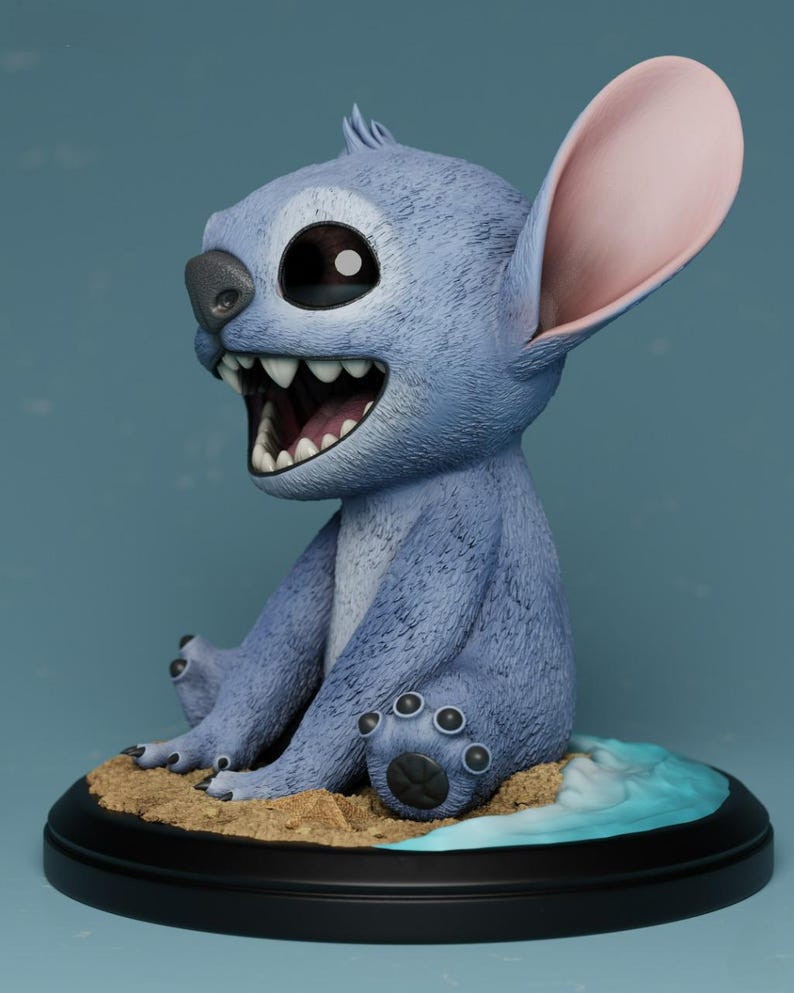 Puede incluir: Una figura azul del personaje Stitch de la pel&iacute;cula Lilo & Stitch. La figura tiene orejas grandes, una amplia sonrisa y est&aacute; sentada sobre una base con detalles de arena y agua. La figura mide aproximadamente 15 cm de altura.