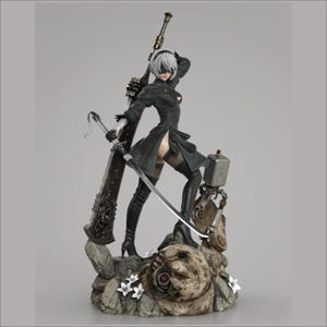May include: A detailed figurine of a female character in a black dress and high boots, holding a sword and a large weapon. The figure has white hair and is standing on a rocky base with white flowers. A small robot is also present.
