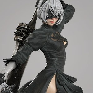 May include: A detailed collectible figurine of a character with short white hair, wearing a black dress with a chest cutout, a black blindfold, and white gloves. The figure holds a large, weathered metallic sword resting against their back.