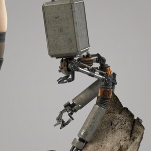 May include: A mechanical robot figure with a rectangular, metallic head featuring a small antenna. The body consists of articulated, weathered silver and copper-toned limbs with claw-like hands, positioned in a seated posture upon a textured rock.