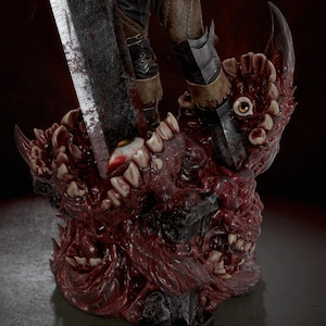 May include: A detailed collectible figurine base featuring a mass of organic, fleshy textures with multiple human-like eyes and rows of sharp teeth. A large, weathered metal sword is embedded into the center of the grotesque, dark red mass.