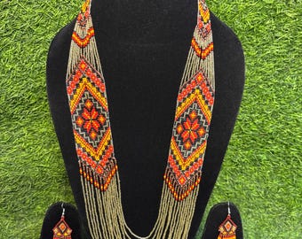 May include: A beaded necklace and matching earrings set. The necklace features a geometric design in red, orange, yellow, and black beads. The earrings have a similar design. The necklace has multiple strands of gold-colored beads.