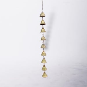 Peut inclure: Un carillon suspendu avec huit petites cloches dorées suspendues à une chaîne. Les cloches sont disposées verticalement, chacune avec une base arrondie et une ouverture évasée. Le fond est blanc uni.