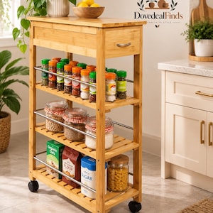 May include: A tall, narrow bamboo kitchen storage trolley on four black wheels. It features a top drawer with a silver handle and three open shelves with silver metal rails. The shelves hold various spice jars, glass canisters, and food boxes.