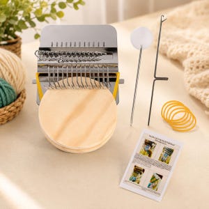 May include: A metal darning loom tool with a round wooden base, a set of metal hooks, a long needle with a white top, a thin metal rod with a hook, several yellow elastic bands, and a small instructional card with text and four images.