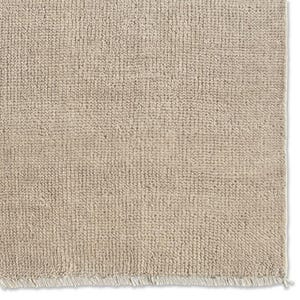 May include: A light beige rug featuring a dense, textured pile surface with a consistent looped weave pattern. The bottom edge of the rectangular rug is finished with a short, straight fringe consisting of numerous thin, light-colored threads.