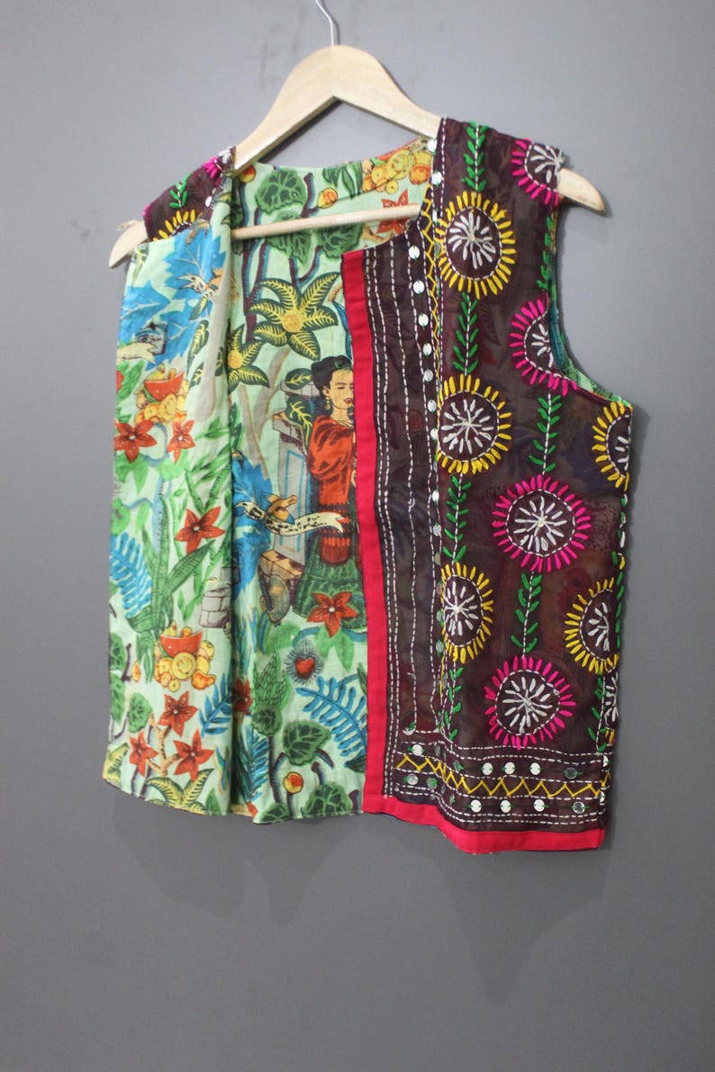 Puede incluir: Un chaleco sin mangas con un estampado floral y de figuras colorido. El chaleco presenta un panel bordado marr&oacute;n con detalles de espejo y un ribete rojo. El forro interior tiene un estampado floral verde y azul.