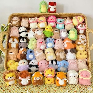 Puede incluir: Una colección de figuras de animales de ganchillo hechas a mano en una cesta de mimbre. Las figuras son de varios colores y diseños, incluyendo osos, pandas y leones. La cesta está hecha de un material tejido de color marrón claro.