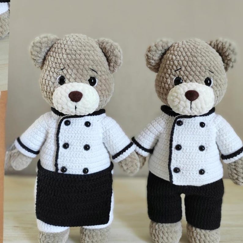 May include: Two handmade crochet teddy bears wearing chef outfits. The bears have light brown fur, white chef coats with black trim and buttons, and black bottoms. One bear wears a black apron. The bears have brown noses and black eyes.