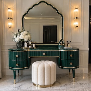 Può includere: Una toeletta verde scuro con piano in marmo, finiture dorate e frontali dei cassetti scanalati, dotata di un grande specchio smerlato e di un pouf cilindrico abbinato color crema, imbottito e con una base circolare dorata.