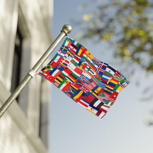 Könnte beinhalten: Eine rechteckige Flagge an einem silbernen Metallmast, die eine Collage aus zahlreichen internationalen Nationalflaggen in verschiedenen Farben wie Rot, Weiß, Blau, Gelb, Grün und Schwarz zeigt, die in einem Rastermuster auf dem Stoff angeordnet sind.