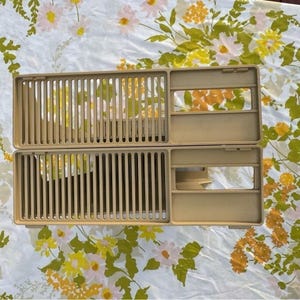 May include: A rectangular beige plastic dish drying rack featuring a slatted base for drainage and a solid side compartment with two rectangular openings. The structure is composed of two identical stacked sections with vertical slots.