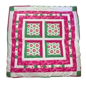Può includere: Una trapunta quadrata caratterizzata da una griglia centrale di quattro blocchi con un motivo floreale bianco e rosso su sfondo verde. La trapunta è incorniciata da bordi alternati di rosa tinta unita, bianco e un motivo a scacchi verde e bianco.