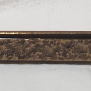 以下が含まれることがあります： テクスチャ加工された中央パネルと2つの取り付けボルトを備えた、ブロンズトーンのキャビネットプル。 長方形のハンドルは、装飾的でまだら模様の表面を持っています。 このハードウェアは、家具やキャビネット用に設計されています。