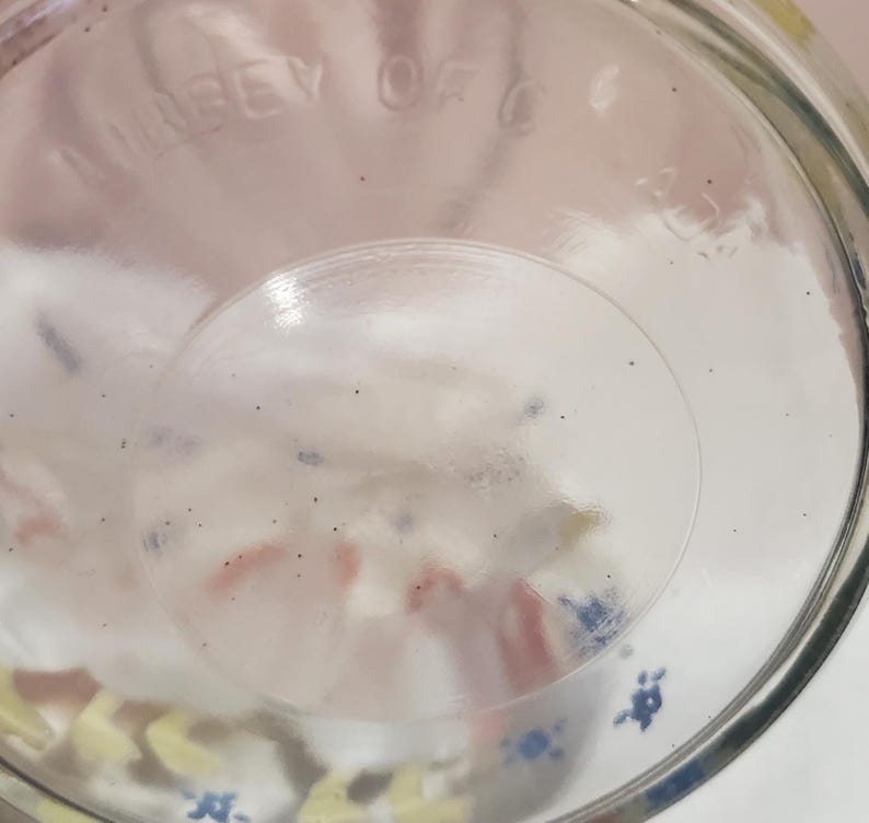 K&ouml;nnte beinhalten: Ein klares Glasgef&auml;&szlig; mit rundem Boden und leicht strukturierter Oberfl&auml;che. Das Gef&auml;&szlig; hat eine weite &Ouml;ffnung und ein klares, transparentes Aussehen. Auf dem Boden des Glases befindet sich schwer lesbarer Text. Das Glas steht auf einer wei&szlig;en Oberfl&auml;che.