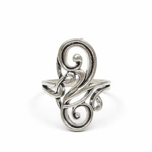 May include: A silver-colored ring with an openwork design featuring swirling, scroll-like patterns. The ring has a band and an ornate centerpiece with multiple curls and curves, creating an elegant, artistic look.