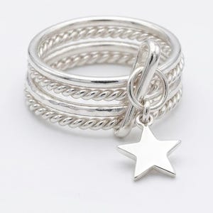 May include: A white ceramic mug with a black handle and the text "But First, Coffee" in a black, handwritten-style font. The mug is on a white surface.