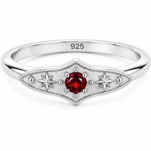 Può includere: Un anello in argento sterling con punzone 925 all'interno della fascia. Il centro presenta una pietra preziosa rotonda rosso scuro incastonata su una placca testurizzata a forma di marquise, affiancata da due stelle incise e perline.