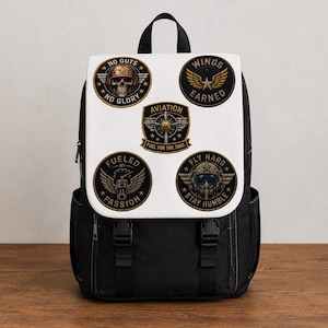 May include: Black backpack with a white flap featuring aviation-themed patches. Patches include phrases like "No Guts No Glory," "Wings Earned," and "Fly Hard Stay Humble." The backpack has black straps and buckles.