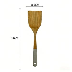May include: A wooden spatula, 34cm long and 8.5cm wide, with a light brown wooden head and handle. The handle has a silver-coloured metal base with a hole for hanging. The spatula is designed for cooking and food preparation.