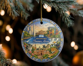 May include: A round ceramic ornament featuring a colourful illustration of Argentina and Buenos Aires landmarks, including the Obelisk, Casa Rosada, a toucan, a jaguar, and penguins, with the text "ARGENTINA Buenos Aires" and a gold hanging string.