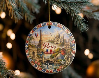 May include: A round ceramic ornament featuring a detailed illustration of Paris landmarks including the Eiffel Tower, Sacré-Cœur, and the Arc de Triomphe. The text Paris and France is printed in the centre above a small French flag and two white swans.