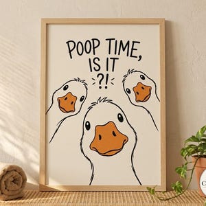 May include: A framed wall art print featuring three white geese with orange beaks looking forward. The text POOP TIME, IS IT?! is printed in black above the geese. The print is enclosed in a light-colored wooden frame with a clean, simple design.