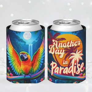 May include: Two beverage can coolers with tropical designs. One features a colorful parrot with outstretched wings, a waterfall, and a full moon. The other has the text "Another Day in Paradise" with palm trees and a sunset.