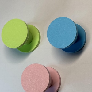 May include: Three circular wall hooks in bright matte colors. One hook is lime green, one is light blue, and one is soft pink. Each hook features a flat, round front face attached to a cylindrical base, designed for mounting onto a flat surface.