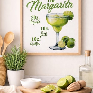May include: A framed cross-stitch art piece with a margarita recipe. The green text reads "The Margarita" with ingredient measurements: 20 oz. tequila, 10 oz. lime juice, and 10 oz. water. The image includes a margarita glass and limes.