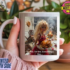 Peut inclure: Mug en céramique blanche avec une image humoristique d'une poupée tenant une dinde rôtie à une table de Thanksgiving chaotique. Le texte sur la tasse dit : "It's fine. I'm fine. Everything's fine...." La tasse est imprimée des deux côtés.
