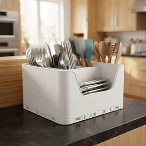 May include: A white plastic kitchen utensil organizer with a low front cutout, containing stainless steel forks, spoons, and knives, along with silicone spatulas and wooden spoons arranged in separate compartments for organized storage.