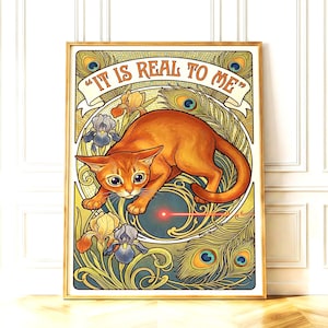 Puede incluir: Una impresión artística enmarcada que presenta un gato naranja con ojos grandes, acechando un punto rojo láser. La obra de arte incluye plumas de pavo real, iris y el texto "IT IS REAL TO ME" en una pancarta, todo dentro de un marco dorado.