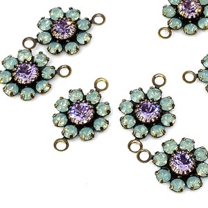 May include: Ten antique gold-toned metal flower-shaped charms with light blue and purple rhinestones. Each charm has three loops for attaching to jewelry.