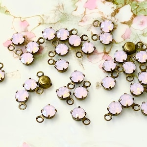 May include: A collection of 18 antique brass connectors with pale pink opal rhinestones. Each connector has two loops and a single rhinestone.