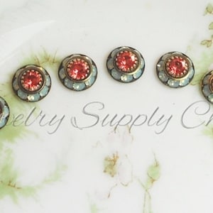 Peut inclure: Six petits embellissements ronds décoratifs avec un motif bleu clair et or et un strass rouge au centre.