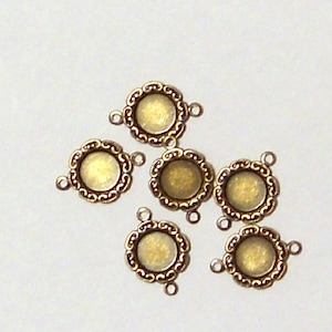 May include: Six gold-toned metal round bezel settings with three loops on each. The bezels have a decorative edge and a smooth, slightly textured surface.