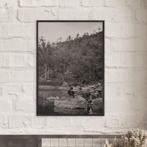 Könnte beinhalten: Schwarz-Weiß-Druck in einem Rahmen eines Vintage-Fotos, das zwei Figuren in der Nähe eines Gewässers zeigt. Das Foto zeigt eine Landschaft mit Bäumen und einem Hügel im Hintergrund. Die Figuren sind in Kleidung aus der Zeit gekleidet.