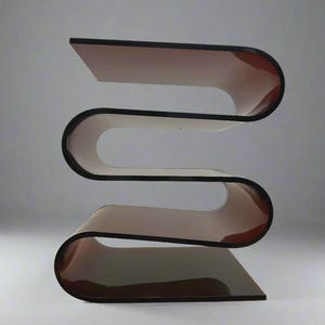 May include: A modern, sculptural side table with a unique, wave-like design. The table features a layered construction with a brown-tinted, curved surface and black edges. The overall shape is reminiscent of the letter "S".