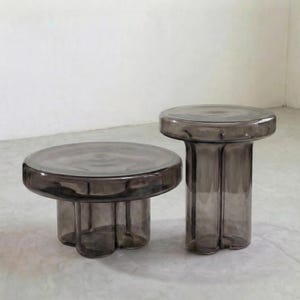 Może przedstawiać: Zestaw trzech ceramicznych kubków z nakrapianym, matowym wykończeniem. Kubki są w odcieniach kremu, jasnoszarym i ciemnoszarym. Każdy kubek ma prosty, minimalistyczny design i zaokrąglony uchwyt.