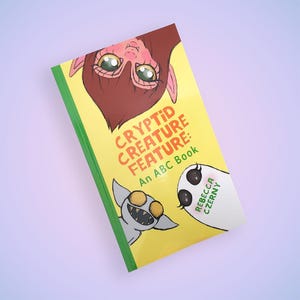 May include: A children's book titled "Cryptid Creature Feature: An ABC Book" with illustrations of cartoon cryptids. The cover is yellow with green trim and features a brown creature, a gray creature, and a white ghost-like creature.