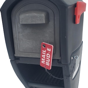 May include: A black mailbox with a red flag and a red tag that says "MAIL BUD-E". The mailbox has the text "U.S. MAIL" on the front.